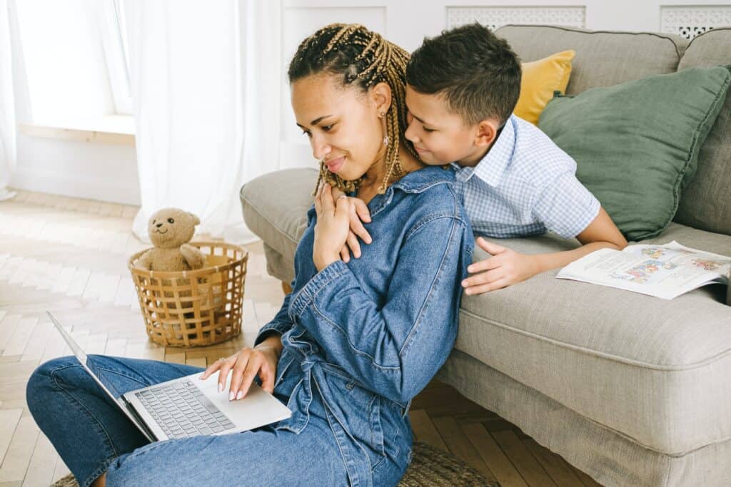 woman looking at laptop with young son behind her